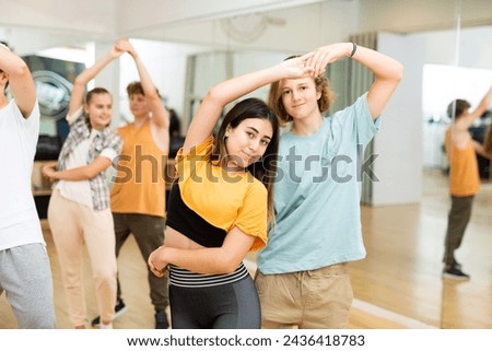 Teenager girls and boys dancing salsa in ballroom together.
