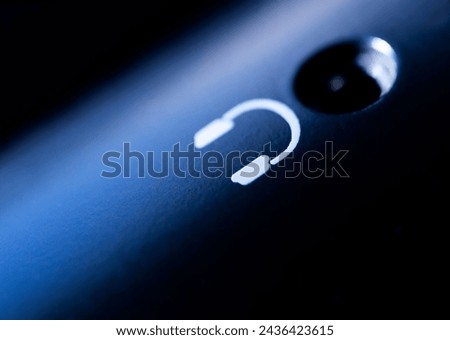 closeup of headphone symbol printed next to the audio input of a device. High contrast and dark background