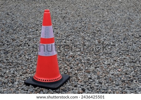 Orange funnel use for beware car on the road under construction. with a pebble background 