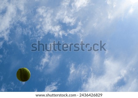 Softball in the air with blue sky background