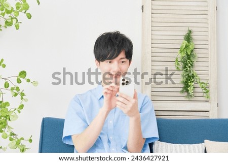Asian man using the smartphone in the living room