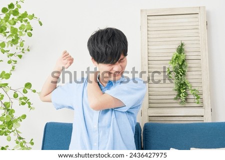Asian man having stiff shoulders in the living room Royalty-Free Stock Photo #2436427975