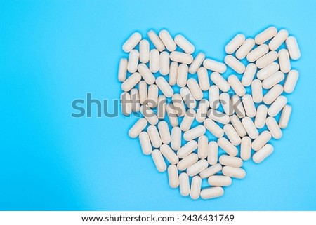 Top view of pills forming a heart, concept of taking care of your health, self-love, self-esteem, daily dose, isolated on blue background with copy space Royalty-Free Stock Photo #2436431769