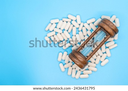 Hourglass next to scattered pills concept of daily dose, take your medicine on time, illness, medicine with copy space Royalty-Free Stock Photo #2436431795