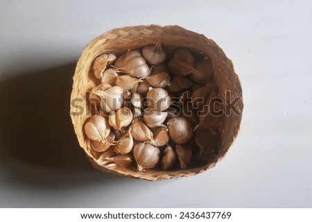 The photo looks from above of some garlic in a wooden container. Garlic is used as the main spice in several Indonesian dishes