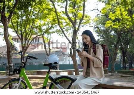 Beautiful woman taking a bike stroll in the park, business woman holding smartphone using bike rental,  business woman holding smartphone using bike rental digital phone.