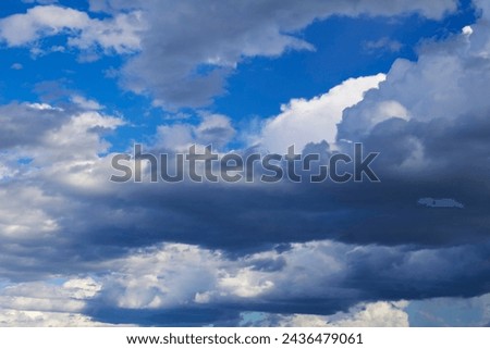 Fluffy white cumulus clouds with some cumulostratus  formations on a late summer afternoon are contrasted against the Australian sky creating a fascinating cloud scape with darker rain clouds. Royalty-Free Stock Photo #2436479061