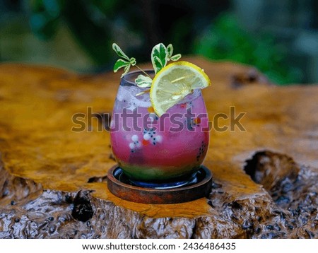 This fresh and cool pink drink is mixed with green basil seed soda syrup and garnished with a lemon wedge Royalty-Free Stock Photo #2436486435