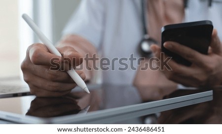 Female doctor working, using digital tablet and mobile phone at doctor's office. writing prescripstion, recording patient's information, healthcare and medicine concept, close up