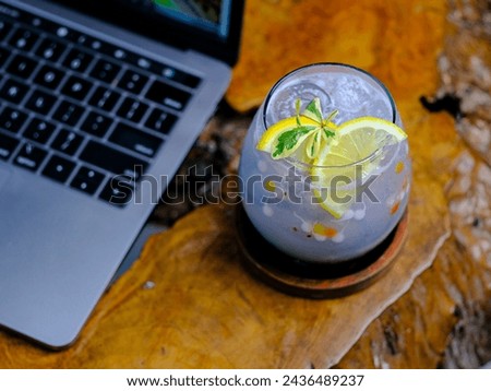 This fresh and cool purple drink is combined with green basil seed soda syrup and garnished with a lemon slice Royalty-Free Stock Photo #2436489237