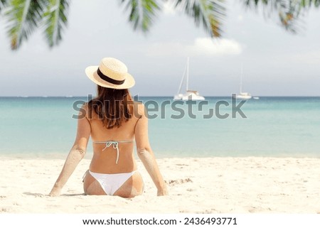 Woman sitting on the sea beach enjoying and relaxing in summer