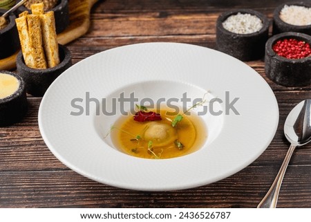 Ravioli consomme on a white porcelain plate. Healthy eating concept Royalty-Free Stock Photo #2436526787