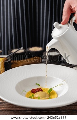 Ravioli consomme on a white porcelain plate. Healthy eating concept Royalty-Free Stock Photo #2436526899