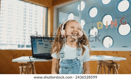 Little pretty caucasian girl smiling to camera while laughing in funny mood. Young child wearing headphone and casual dress standing while looking at camera with satisfy, happy, joyful. Erudition.
