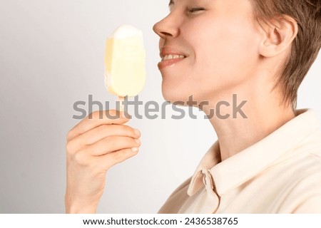 A woman in her middle years enjoys ice cream against a pristine white background, relishing the frozen delight with each delightful lick Royalty-Free Stock Photo #2436538765