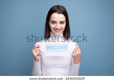 A young girl put on a medical mask incorrectly. The woman shows an error while wearing a mask. Royalty-Free Stock Photo #2436543229