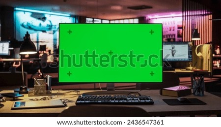 Desktop Computer with Mock Up Green Screen Chroma Key Display Standing on the Desk in the Empty Creative Office Lit by Neon Lights. Monitor in Game Development or Animation Company