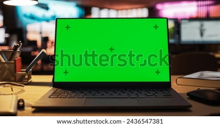 Laptop Computer with Green Screen Standing on a Wooden Desk with Height Adjustable Function. Chroma Key Display in Empty Decorated Creative Office for Game Development Startup