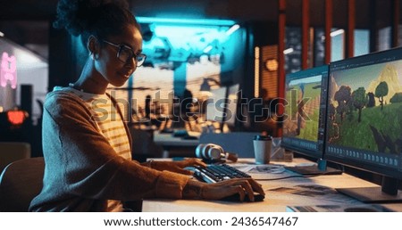 Portrait of Female Video Game Designer Working on a New 3D Level on Desktop Computer in Creative Office. Black Focused Woman Creating Metaverse and Adding Details to a Game Environment Royalty-Free Stock Photo #2436547467