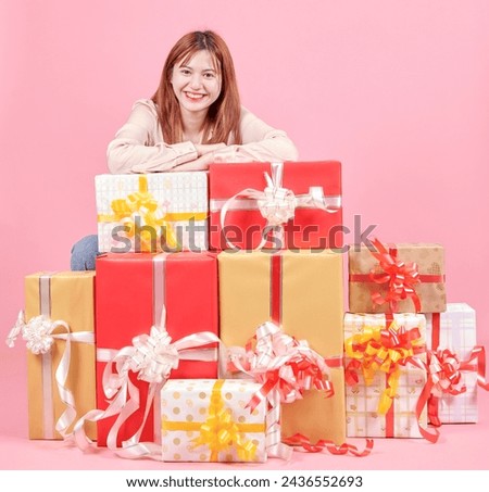 Photo of pretty adorable woman in pink shirt standing holding stack of gift boxes over pink studio background. celebrating women's day, valentine's, birthday, anniversary. shopping for holiday concept