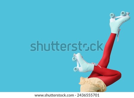 Beautiful young woman in vintage roller skates on blue background, closeup Royalty-Free Stock Photo #2436555701