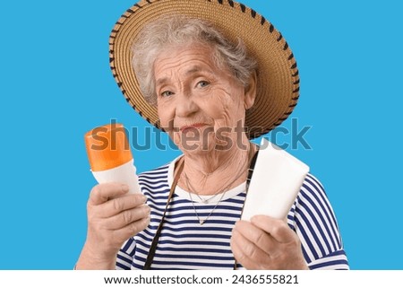 Senior woman with sunscreen cream on blue background, closeup