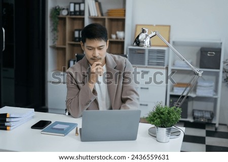 Happy young man smiling while reading smartphone, smiling businessman reading text with smartphone In the office, man works at his desk.
