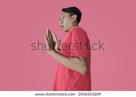 Portrait of young Asian man shocked to see something on his side, excited gesture with copy space, against pink background