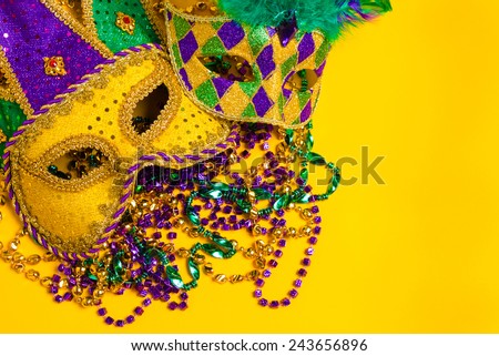 A group venetian, mardi gras mask or disguise on a yellow background with strings of beads