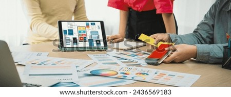Cropped image of interior designer team chooses color from color swatches while tablet displayed UI and UX designs for mobiles app and website. Creative design and business concept. Variegated.