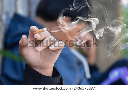 Closeup teenager's hand holding lighted cigarrette in private area, white smoke edited, concept for bad habit and drug's addiction of teenagers, new edited.