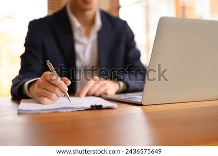 Businessman in black suit signing contract paper at his office desk