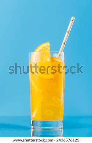 Lemonade with ice in glass over blue background