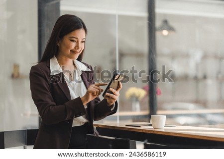 Beautiful young millennial Asian woman using a smartphone at a cafe. Portrait of a gorgeous smiling female engrossed in her mobile phone