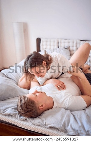 young beautiful couple playing and wrestling on the bed, minimalism