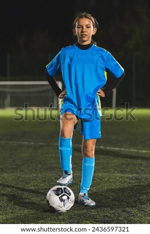 a soccer player teenage girl holding her leg on a ball and posing for the camera in the evening. High quality photo