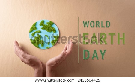 Hands holding paper earth with grass on brown background. World environment day, earth day and save earth concept. Royalty-Free Stock Photo #2436604425