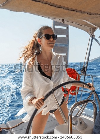 Blond Female sailboat yacht captain at the helm sailing in the Mediterranean Sea