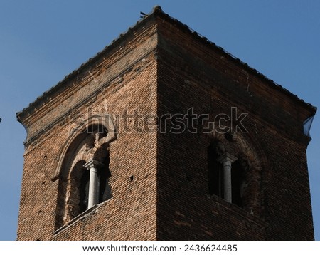 Ferrara, Italy. Top of the ancient Torre dei Leuti, a 9th century military defensive structure. Since the 15th century it has been used as the bell tower of the nearby church of San Paolo. Royalty-Free Stock Photo #2436624485