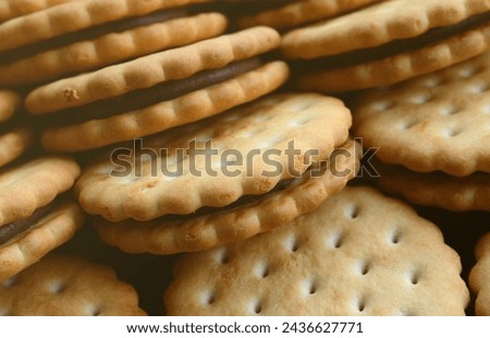 Detailed picture of round sandwich cookies with coconut filling. Background image of a close-up of several treats for tea.