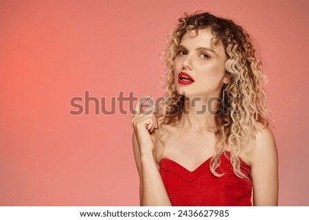 charming woman with wavy hair and perfect skin applying perfume on pink and yellow backdrop
