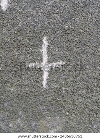 Plus symbol on cement wall.
