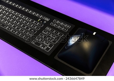 Built-in tabletop industrial input device with black keyboard and trackball mouse. Modern electronic navigation equipment mounted at the captains bridge Royalty-Free Stock Photo #2436647849