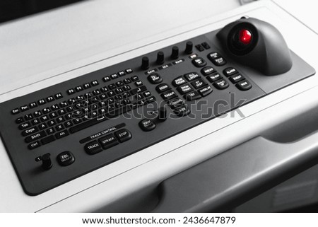 Built-in tabletop input device, black industrial keyboard with a trackball mouse, modern navigation equipment mounted on a control panel at captains bridge. Marine navigation simulation system Royalty-Free Stock Photo #2436647879
