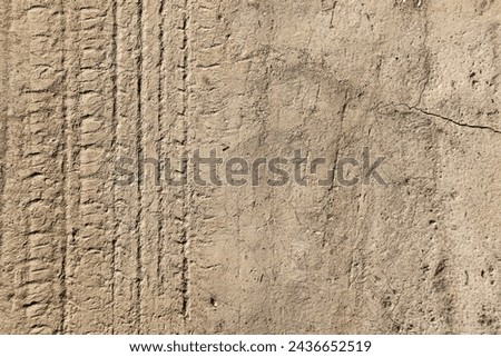 car tire tracks imprint on dry cracked clay Royalty-Free Stock Photo #2436652519