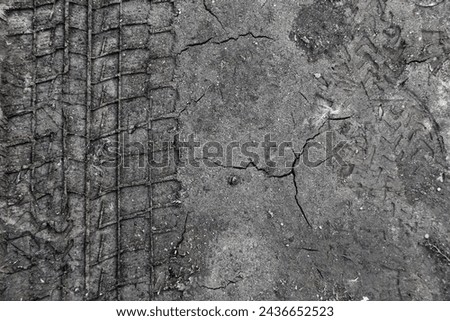 car tire tracks imprint on cracked black soil Royalty-Free Stock Photo #2436652523