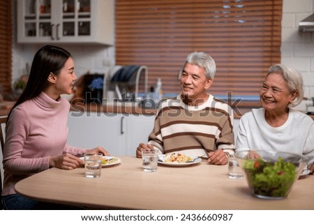 Asian lovely family having dinner enjoy eating party in house together. Attractive senior elderly grandparent and young beautiful daughter eat foods celebrate weekend reunion at dining table at home.