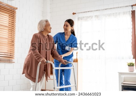Asian senior older woman patient doing physical therapy with caregiver. Attractive specialist carer women help and support elder mature female practice walking slowly with walker at nursing home care.