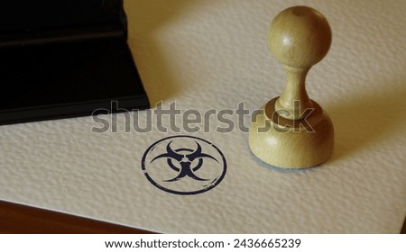 Biohazard warning stamp and stamping hand. Biological hazard symbol concept. Royalty-Free Stock Photo #2436665239