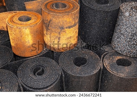 Old black sheet rubber and two rolls of brown rubber on top, rolled into rolls, top view. rubber waste.